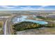 Panoramic aerial view showcasing a vibrant community with a large turquoise lagoon, homes, and roads at 9893 Branching Ship Trce, Wesley Chapel, FL 33545