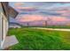 Fenced backyard with green grass, partial view of pond and a glimpse of a screened lanai at 9893 Branching Ship Trce, Wesley Chapel, FL 33545