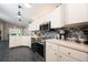 Well-lit kitchen with white cabinets, black appliances, tile backsplash, and gray tile flooring at 10321 Ravines Dr, New Port Richey, FL 34654