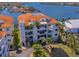 Multi-story waterfront condo with orange tile roof, balconies, and tropical landscaping at 1042 Bellasol Way # 202, Apollo Beach, FL 33572
