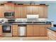 Kitchen featuring stainless steel appliances, ample wood cabinetry, granite countertops, and a mosaic tile backsplash at 1042 Bellasol Way # 202, Apollo Beach, FL 33572
