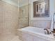 This pristine main bathroom features a tiled shower, built-in bath, and tile flooring at 1042 Bellasol Way # 202, Apollo Beach, FL 33572