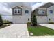 Townhome with a gray and beige facade, two-car garage, modern landscaping, and a brick-paved driveway at 10712 Oak Bend Dr, Parrish, FL 34219