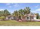 Beautiful home featuring stone accents, a well-manicured lawn, and tropical palm trees for a serene setting at 11296 Warm Wind Way, Weeki Wachee, FL 34613
