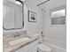 Bright bathroom features a granite vanity, a framed mirror, and a shower-tub combination with tiled walls at 12327 Glenfield Ave, Tampa, FL 33626