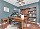 Stylish home office featuring dark teal walls, built-in bookshelves, and a large wooden desk with modern monitor at 12327 Glenfield Ave, Tampa, FL 33626