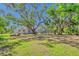 Picturesque backyard featuring an enclosed pool area, lush green lawn, and mature trees offering ample shade at 13483 Heritage Way, Sarasota, FL 34240