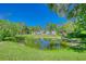 Expansive green backyard view with surrounding trees and a pristine pond reflecting the sky at 13483 Heritage Way, Sarasota, FL 34240