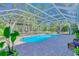 Backyard pool area features a screened enclosure, brick pavers, seating area, and lush landscaping at 13483 Heritage Way, Sarasota, FL 34240