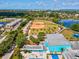 Community aerial view showcasing a baseball field, pool, and splashpad amidst tree-lined streets and homes at 1390 S Hillcrest Ave, Clearwater, FL 33756