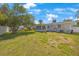This backyard features a lush green lawn, beautiful trees, and plenty of space to relax and unwind at home at 1410 Lime St, Clearwater, FL 33756