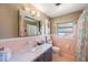Bright bathroom features a large mirror, a window, and light pink tile in this cozy home at 1410 Lime St, Clearwater, FL 33756