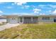 Inviting one-story home with a screened front porch and attached one-car garage, set against a beautiful blue sky at 1410 Lime St, Clearwater, FL 33756