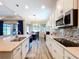 Well-lit kitchen featuring white cabinets, stainless steel appliances, and granite countertops with a mosaic tile backsplash at 1803 Pacific Dunes Dr, Sun City Center, FL 33573