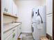 Functional laundry room with white cabinets, a sink, and a stacked washer/dryer unit at 1803 Pacific Dunes Dr, Sun City Center, FL 33573