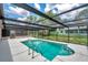 Screened-in pool with ladder and white concrete surrounding the pool area with views of the backyard at 186 Dan River Dr, Spring Hill, FL 34606