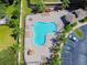 Aerial view of a fenced swimming pool, patio furniture, lush vegetation, and parking lot at 256 Castlekeeper Pl, Valrico, FL 33594