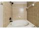 Neutral bathroom featuring a soaking tub, ceramic tile surround, and black fixtures at 256 Castlekeeper Pl, Valrico, FL 33594
