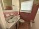 Pink tiled bathroom with a sink, toilet, and vanity needing renovations at 318 Banana St, Tarpon Springs, FL 34689