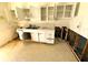 Damaged kitchen features white cabinets and a double sink, awaiting renovation at 318 Banana St, Tarpon Springs, FL 34689