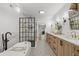 Modern bathroom featuring dual vanities, marble counters, striking tile flooring, a soaking tub, and glass shower at 3215 W Fair Oaks Ave, Tampa, FL 33611