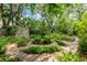 Lush backyard garden with a circular brick path, mature trees, and diverse plants, ideal for relaxation at 4215 Water Oaks Ln, Tampa, FL 33618