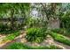 Lush backyard garden with a circular brick path, mature trees, and diverse plants, ideal for relaxation at 4215 Water Oaks Ln, Tampa, FL 33618