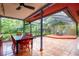 This tiled, screened in patio features a dining table and an adjacent wooden deck at 4215 Water Oaks Ln, Tampa, FL 33618