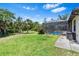 Lush backyard featuring a screened-in patio with a swimming pool and surrounded by tropical trees at 4323 Baynes Rd, North Port, FL 34288