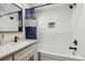 Bright bathroom with white tiled tub/shower, black shower head and hardware, gray countertop and vanity with sink at 4368 Marine Pkwy, New Port Richey, FL 34652