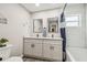 Bathroom with double sink vanity, gray cabinets, framed mirrors, tiled shower and bathtub, and wood-look flooring at 4368 Marine Pkwy, New Port Richey, FL 34652