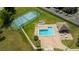 An aerial view of the community pool and tennis court, with lounge chairs, tables, and a nearby parking area at 4520 Wescott Ln, Tampa, FL 33624