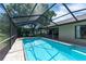 The aerial view shows a clear swimming pool within screened enclosure, nestled among green trees at 5298 Florentine Ct, Spring Hill, FL 34608