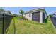 Manicured backyard featuring lush green grass, sleek black fencing, and a screened-in porch at 5548 Silver Sun Dr, Apollo Beach, FL 33572