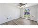 Bright bedroom with modern gray wood flooring, large arched window, and stylish ceiling fan at 6302 Silver Oaks Dr, Zephyrhills, FL 33542