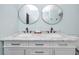 Bathroom featuring a dual vanity with marble countertop, round mirrors, and sleek fixtures at 6600 121St Ave # 4, Largo, FL 33773