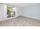 Bright and airy living room featuring wood-look tile flooring, a large window, and a light blue accent wall at 6600 121St Ave # 4, Largo, FL 33773