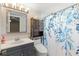 Bright bathroom features a stylish vanity, toilet, and bathtub with blue floral shower curtain at 7025 Orkney N Ave, St Petersburg, FL 33709