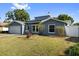 Charming single-story home with a well-manicured lawn, garage and blue door at 7025 Orkney N Ave, St Petersburg, FL 33709