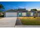 Charming single-story home with a well-manicured lawn, garage and blue door at 7025 Orkney N Ave, St Petersburg, FL 33709