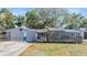 Charming single story home with gray exterior, brick accents, blue door, and an enclosed patio at 9236 Suncoast Terrace, Hudson, FL 34667