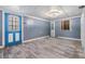 An empty room with wood-look tile, a blue door with windows, and a new light fixture, ready for customization at 9236 Suncoast Terrace, Hudson, FL 34667