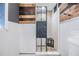 Modern bathroom shower with wood accents, pebble tile, a glass door, and white wainscotting at 9236 Suncoast Terrace, Hudson, FL 34667