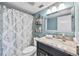 Well-lit bathroom with a marble countertop vanity, patterned shower curtain, and modern fixtures at 10605 Carrollbrook Ln, Tampa, FL 33618