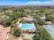 Aerial view showcases a sparkling blue community pool surrounded by lush greenery, lounge chairs, and tennis courts at 1003 Teal Pointe, Tarpon Springs, FL 34689