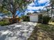 Long driveway leading to an attached two-car garage, adorned by shaded trees and green shrubbery at 1003 Teal Pointe, Tarpon Springs, FL 34689