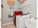 Laundry room with a red washer, white dryer, a utility sink, and a window for natural light at 10528 Bermuda Isle Dr, Tampa, FL 33647