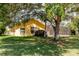 Backyard view with well-maintained grass, large tree, screened lanai, and the back of the yellow house at 11209 Pocket Brook Dr, Tampa, FL 33635