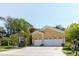 Exterior view of a yellow two-story home with a well-manicured lawn, landscaping, and a three-car garage at 11209 Pocket Brook Dr, Tampa, FL 33635