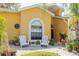 Front porch view with white Adirondack chairs, a small table, lovely landscaping, and a bright yellow house at 11209 Pocket Brook Dr, Tampa, FL 33635